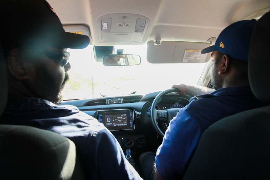 Two men driving a car.