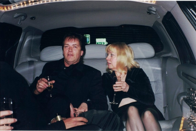 Terrance and Christine Hodson in the back of a limo, each have a glass of champagne.