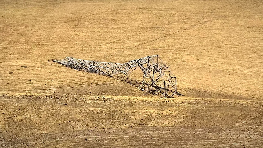 A broken power transmission tower on farmland 
