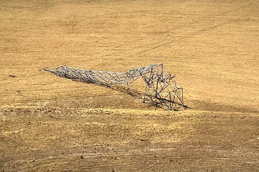 A broken power transmission tower on farmland 
