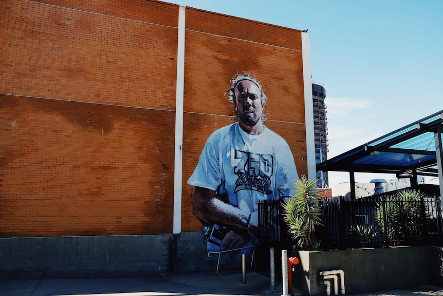 brick wall featuring painting of man wearing a white shirt 