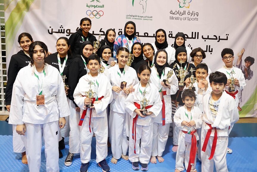 A group of karate students pose with trophies.