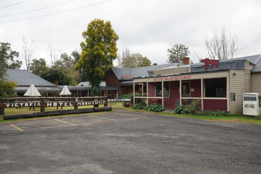 An empty carpark with a sign reading "Victoria hotel Moonan Flat"