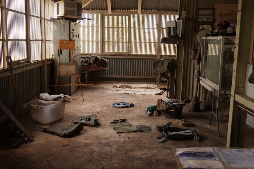 Various items of clothing are littered around a muddy floor. 