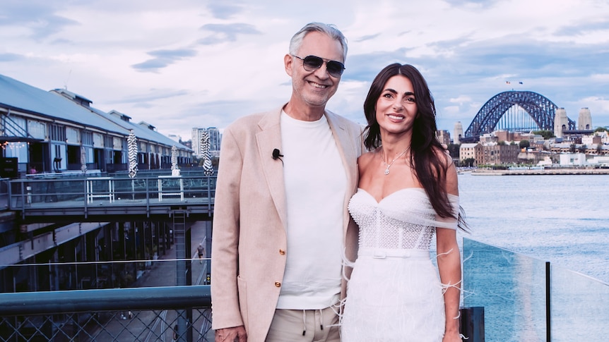 Andrea Bocelli and Silvia Colloca pose for a photo with a view of they Sydney Harbour Bridge in the background.  