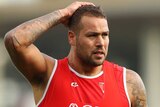 A Sydney Swans AFL player stands with a hand on his head at a training session.