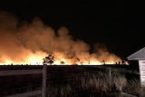 A large bushfire burns at night time.