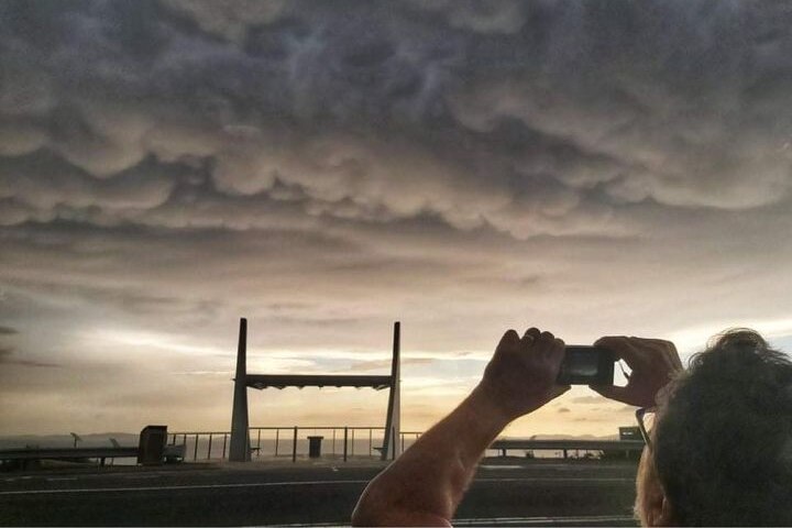 A person takes photo of heavy grey clouds.