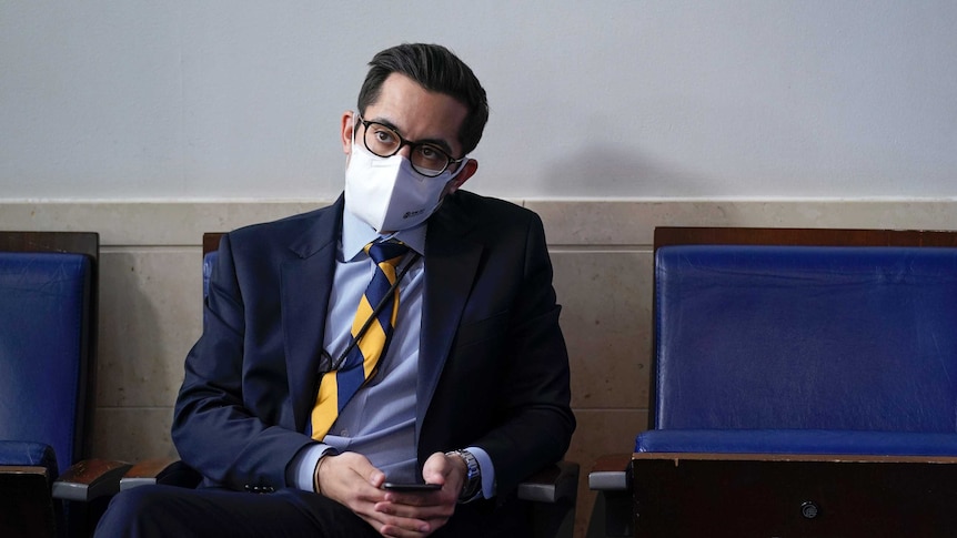 White House deputy press secretary TJ Ducklo sits while wearing a mask