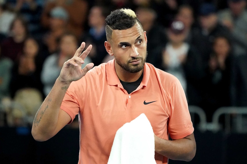 Nick Kyrgios holds his hand up in the air and looks up