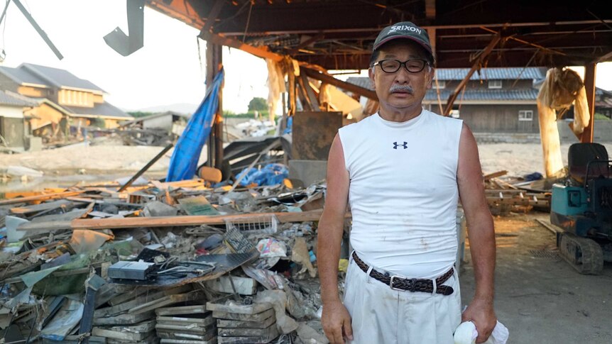 Soji Ono poses for a photo with piles of rubbish and debris behind him.