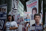 A campaigner stands behind a placard of candidate Baggio Leung.