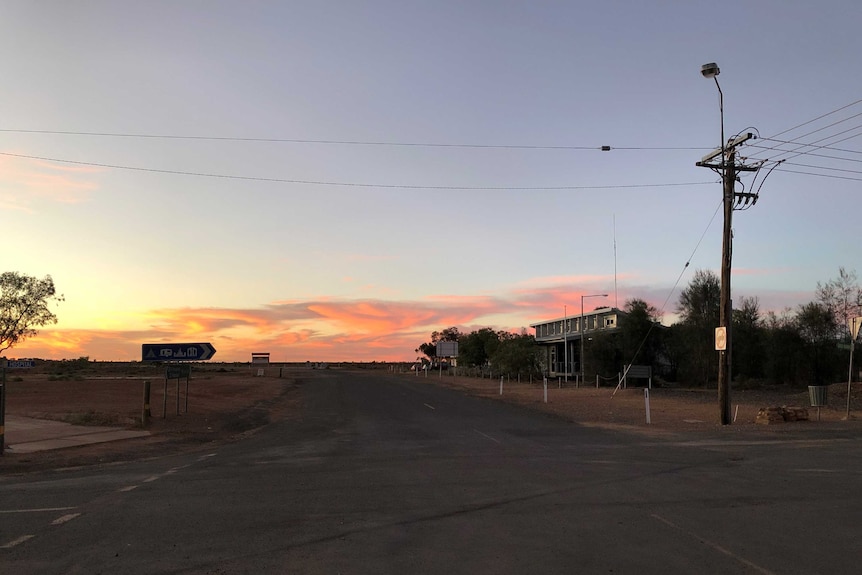 A landscape photo of a sunset over the main road through White Cliffs, looking towards the Broken Hill road.