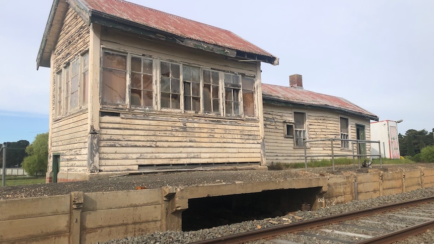 A decrepit disused train station with a faded red roof