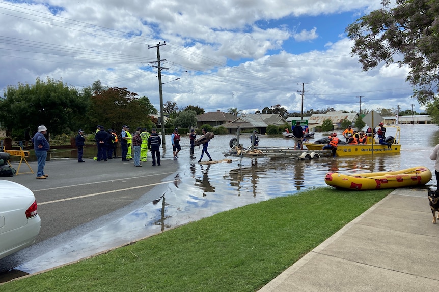 A flood rescue with emergency services in land meet a boat coming in from the flooding town centre. 