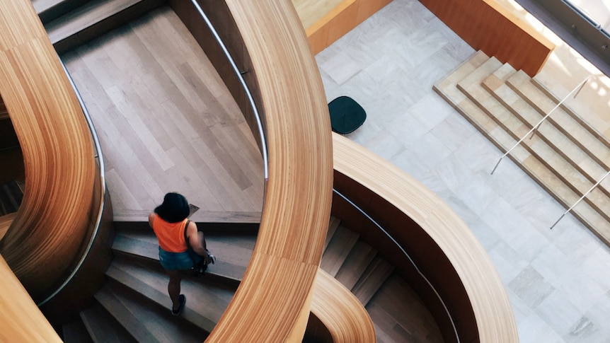 A woman walks on a curved wooden stairwell at the Art Gallery of Ontario, Toronto, Canada.
