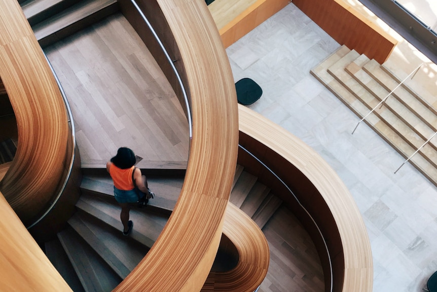 A woman walks on a curved wooden stairwell at the Art Gallery of Ontario, Toronto, Canada.