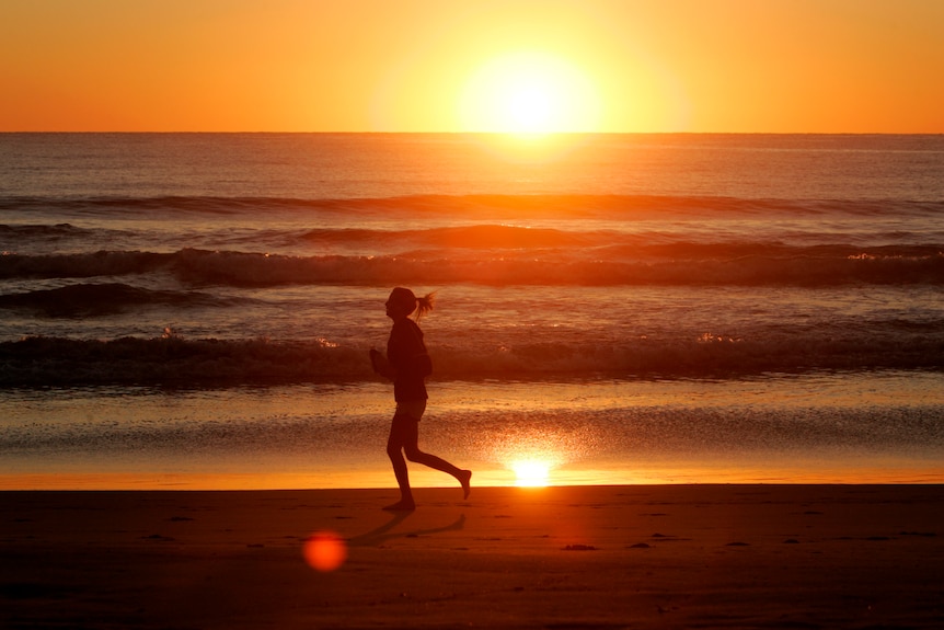 A jogger runs along the shore of Manly Beach after sunrise on the first day of Spring in Sydney, 2008