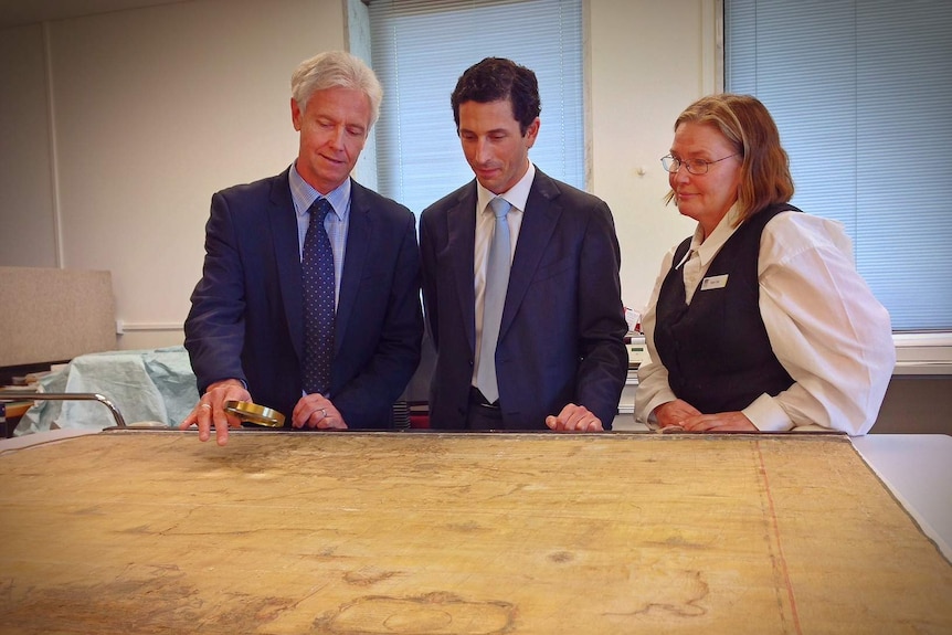 Dr Martin Woods, Ryan Stokes and Robin Tait examine the fragile map.