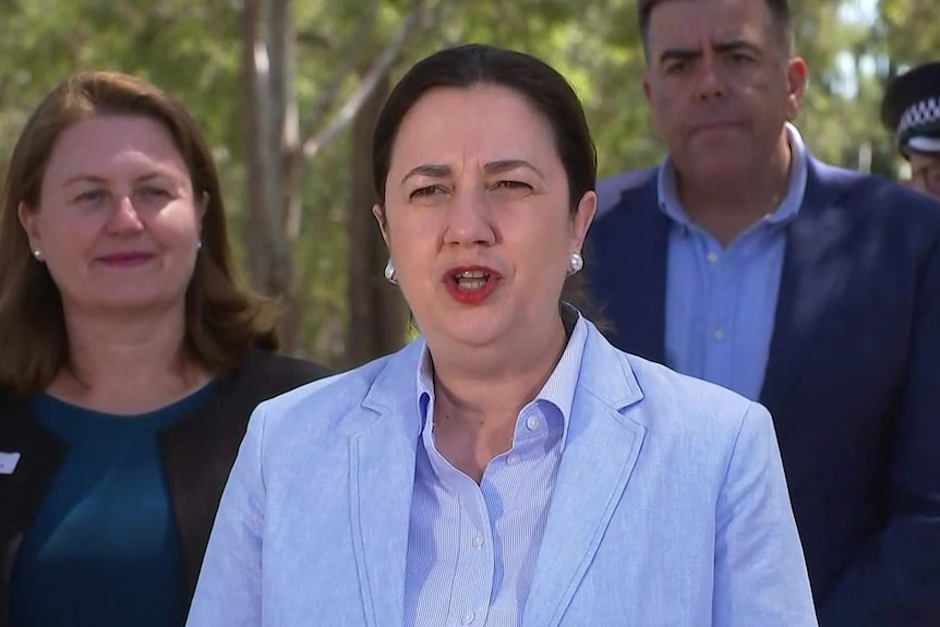 Premier Annastacia Palaszczuk flanked by a group of people in a park