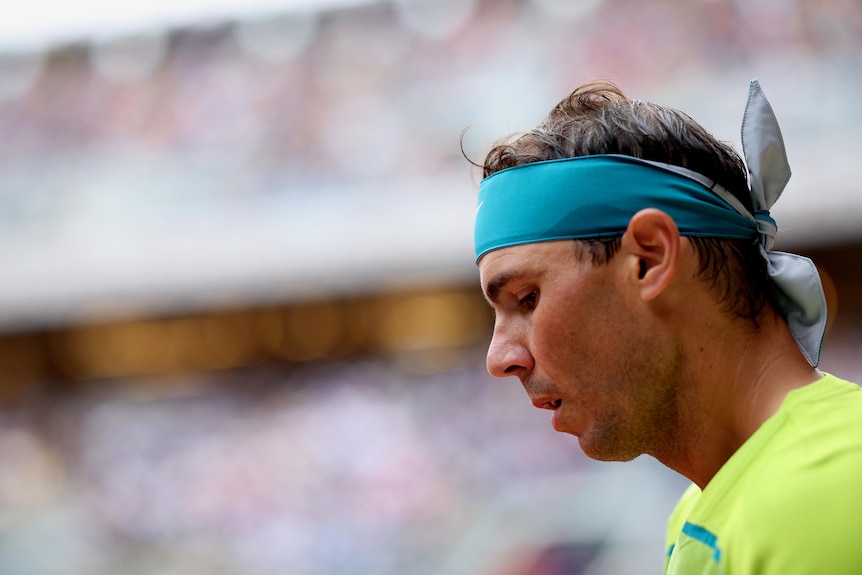 Rafael Nadal looks down with a bandana on his head