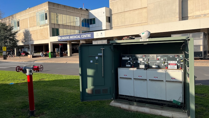 An open power box out the front of a hospital with a hard hat resting on top