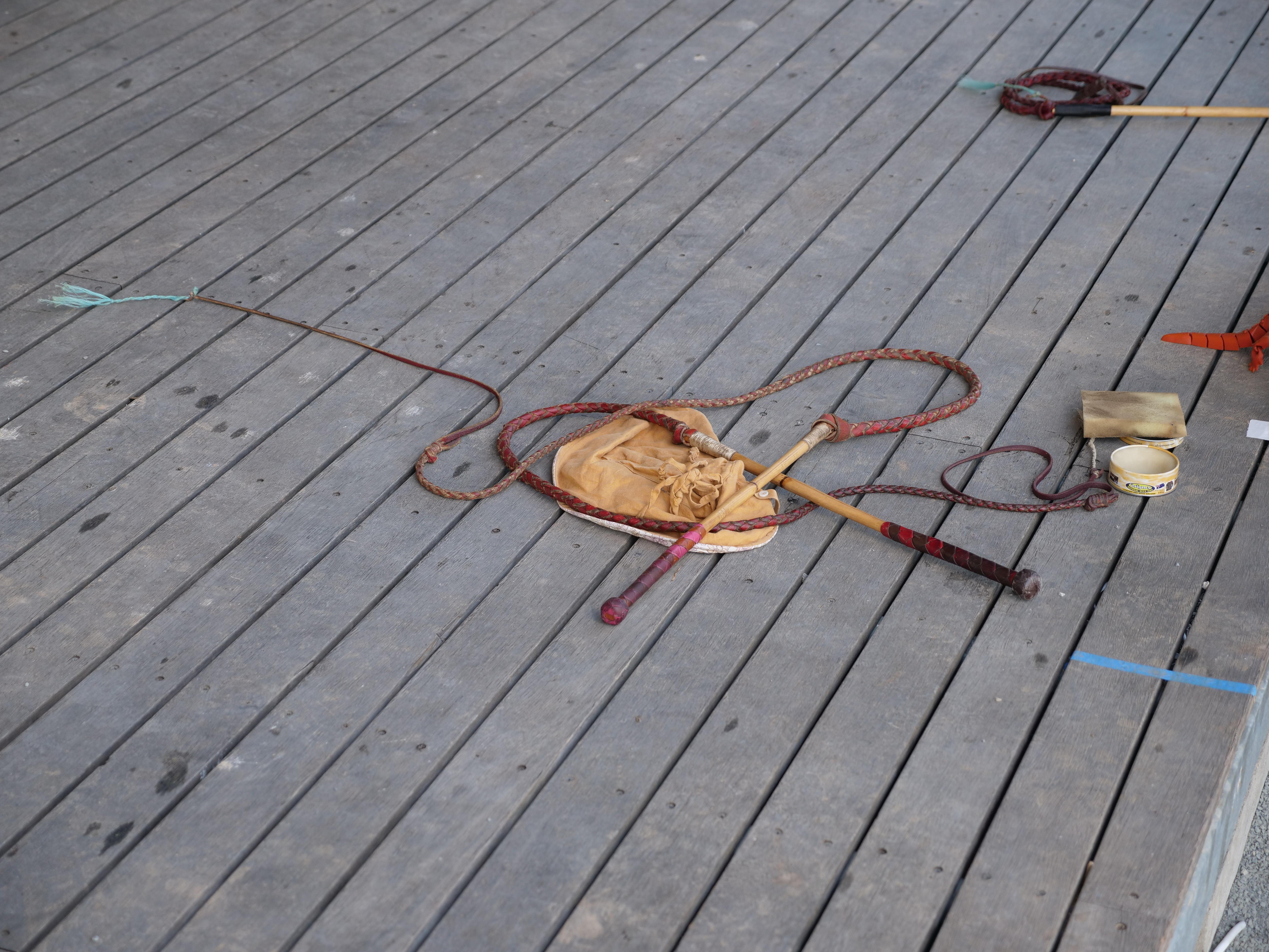 A stock whip placed on a stage's wooden floorboards