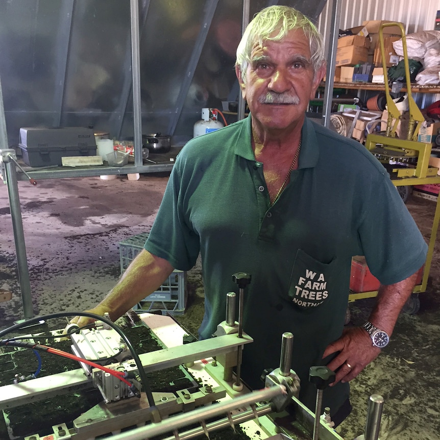 Lou Dimasi stands over machinery in a workshop.