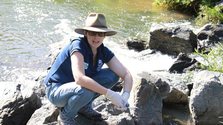 Tamielle Brunt squatting on a rock in the Kedron Brook