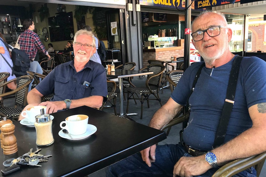 Two men sit at an outdoor cafe.