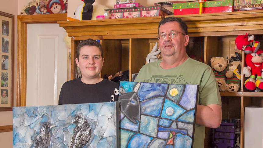 A picture of a teenager and man holding paintings