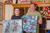 A picture of a teenager and man holding paintings