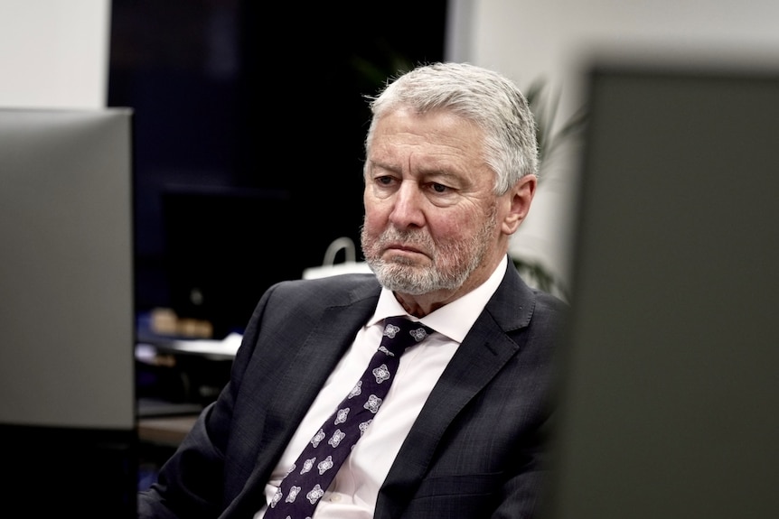 A man in a suit looks at a computer screen.