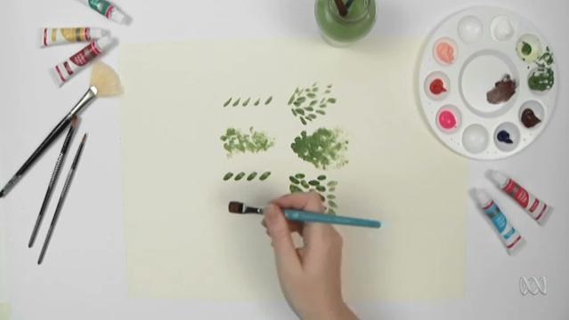 Hand uses paintbrush to make various patterns on paper