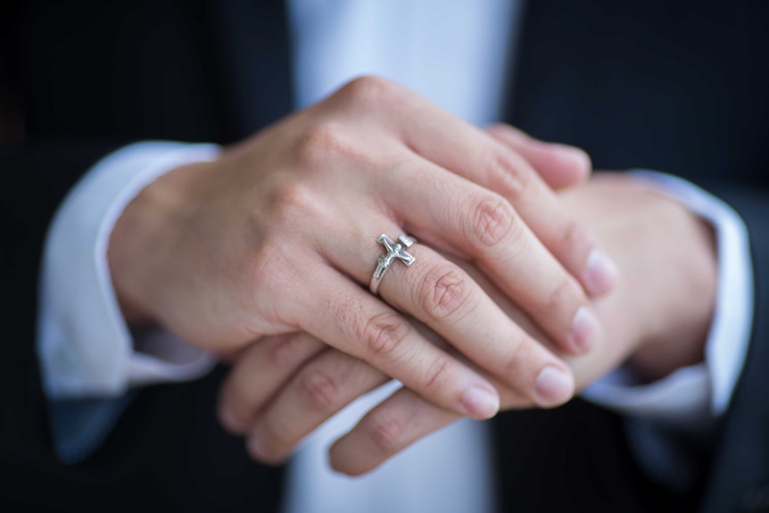 A ring on a man's hands shows Jesus on a crucifix.