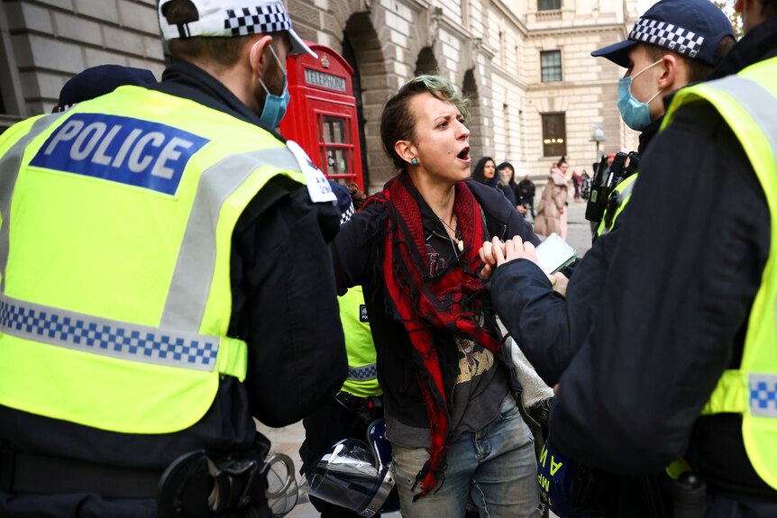 A woman shouts as police surround her.