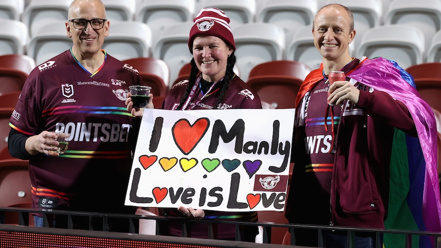 A group of Manly fans hold up a sign reading "I love Manly, love is love."