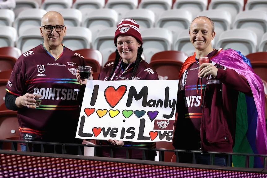 A group of Manly fans hold up a sign reading "I love Manly, love is love."