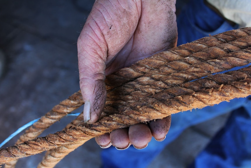 A close-up shot of Peter Weston's hand holding the tightly plaited rope.