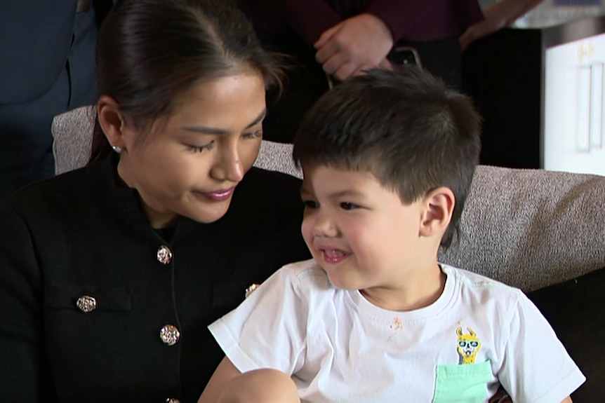 A woman gazes at her child while they are sitting on a couch.