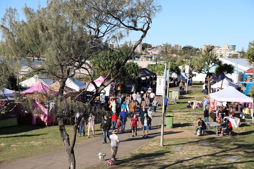 A busy pedestrian strip with market stalls and blue skies