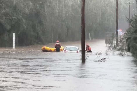 A flooded road and with rescuers in the distance.
