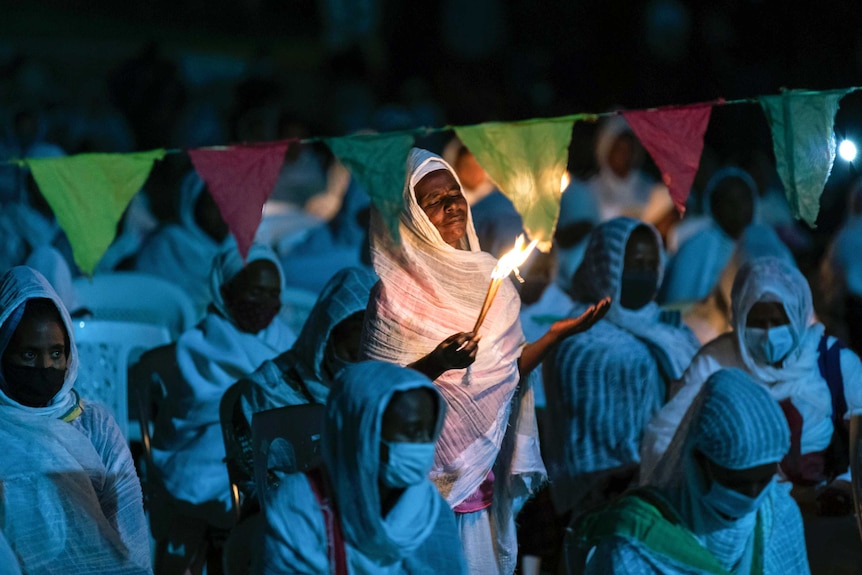 Ethiopian Orthodox Christians light candles and pray for peace during a church service.