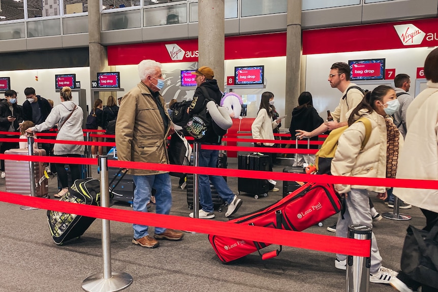 People lined up to check in at Brisbane Airport with red straps showing line-up areas