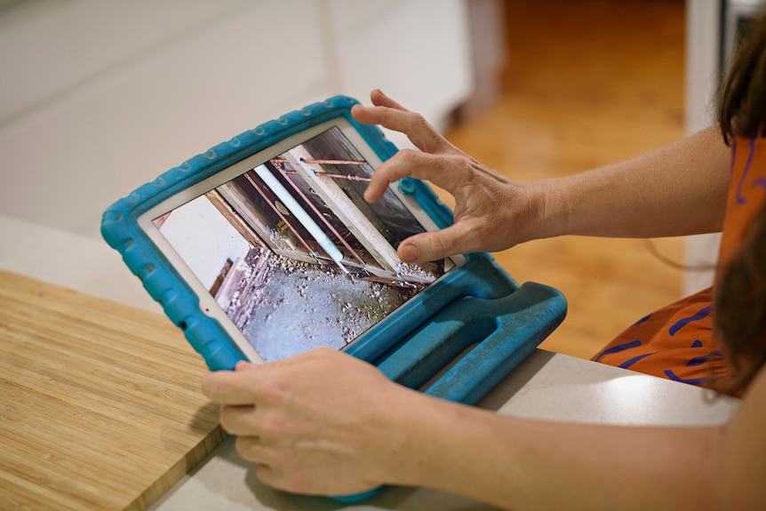 Sue Phoo scrolls through photos of her house being renovated on an iPad.