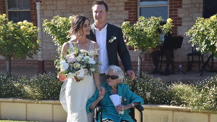 An elderly woman holding the hand of her great-granddaughter on her wedding day.