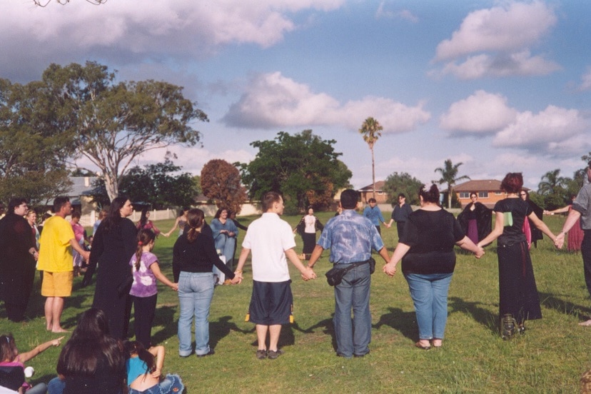 A group of people gather in a circle, holding hands.