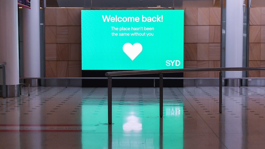 Sign at Sydney Airport's empty international arrivals hall reads "Welcome back! the place hasn't been the same without you".