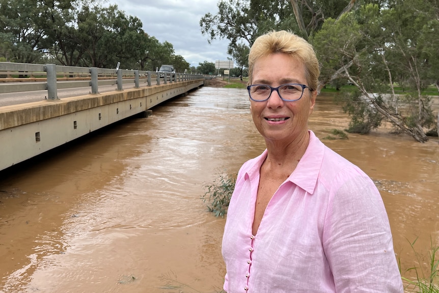 a woman smiling in front of a swelled river