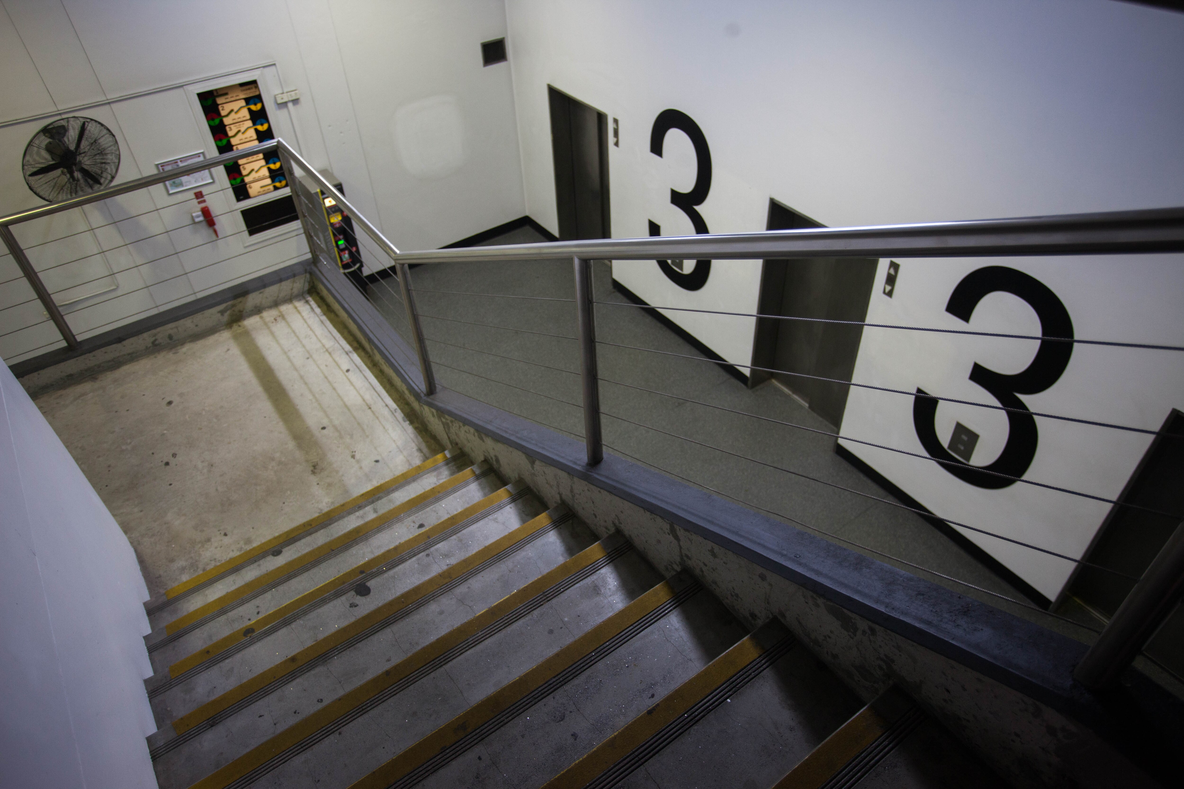Stairs lead down to elevators and the number three written in large on the wall